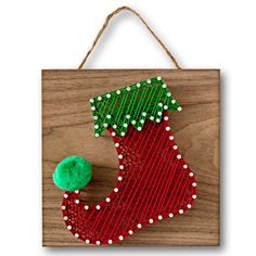 a red and green christmas stocking hanging on a wooden board with white dots around it