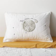 a white pillow sitting on top of a bed next to a yellow blanket and pillows