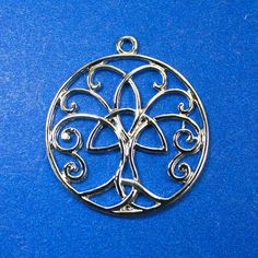 a silver metal pendant with swirly designs on blue background, close up view photo