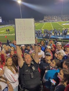 a police officer holding up a sign at a football game