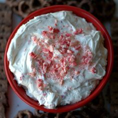 a red bowl filled with white frosting and sprinkles