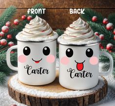 two coffee mugs with frosting on them sitting next to each other in front of a christmas tree