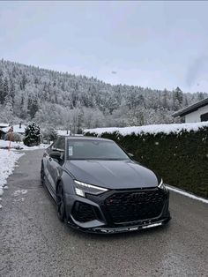 a black car parked on the side of a road in front of snow covered mountains