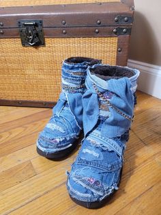 an old pair of blue jean boots sitting on top of a wooden floor next to a suitcase