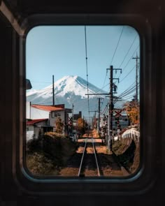 a view of a snow covered mountain from inside a train window, looking down the tracks