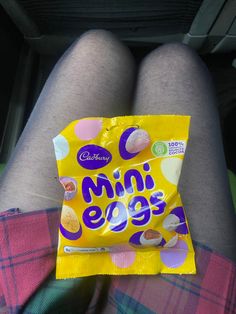 a close up of a person's legs with a bag of candy on their lap