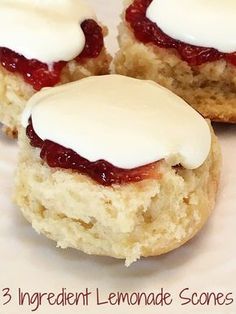 three lemonade scones with white frosting and strawberry jam on top are sitting on a plate