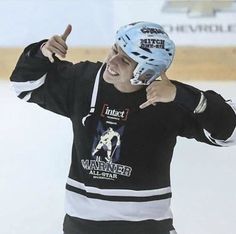 a young man wearing an ice hockey uniform giving the peace sign with his right hand