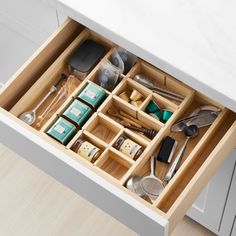 an open drawer in a kitchen with utensils and other items inside the drawers