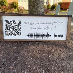 a wooden sign sitting on the side of a road in front of a tree and house