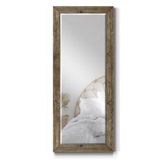 a large mirror hanging on the wall next to a white bed with pillows and blankets