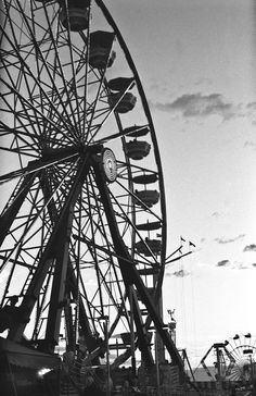 an amusement park ferris wheel in black and white with people standing around it at dusk