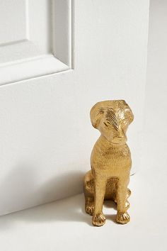 a small golden dog figurine sitting next to a white door handle on a plain surface