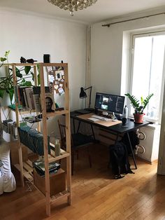 a room with a desk, computer and bookshelf filled with various items in it