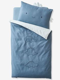 a blue bed with two pillows and a pillow case that has dinos on it