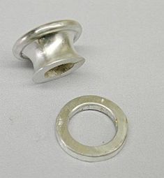 two silver colored metal rings on a white surface with a hole in the middle that has a ring inside it