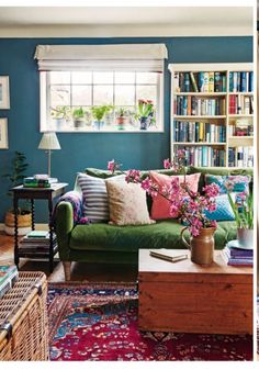 two pictures of a living room with blue walls and green couches in front of bookshelves