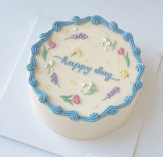 a birthday cake decorated with flowers and the words happy day on it's side