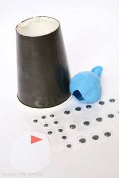 a black and white cup sitting on top of a table next to a ruler with holes in it