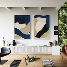 two paintings are hanging on the wall above a coffee table in a modern living room