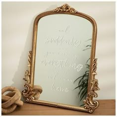 a mirror sitting on top of a wooden table next to a potted green plant