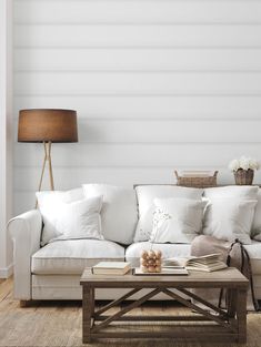 a living room with white couches and pillows on the floor, along with a coffee table