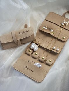 an assortment of jewelry is displayed on a white cloth covered tablecloth with gold and pearl necklaces