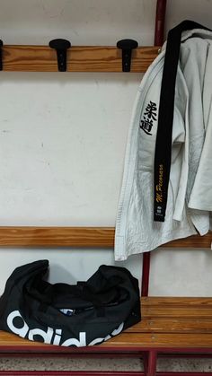 a pair of black shoes sitting on top of a wooden bench next to a white jacket