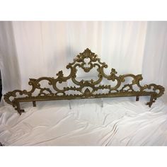 an ornate gold metal headboard on a white sheet