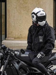 a man sitting on top of a motorcycle in front of a building with columns and pillars