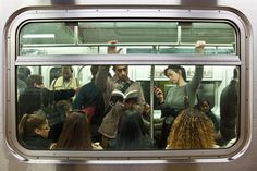 people standing on a subway train looking out the window