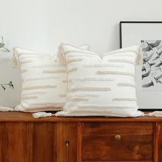 two white pillows sitting on top of a wooden dresser