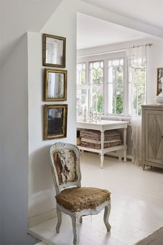 a chair sitting in the middle of a room next to a wall with pictures on it