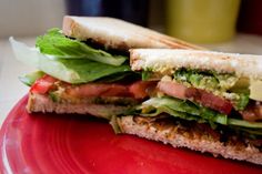 a sandwich with lettuce, tomato and other toppings on a red plate