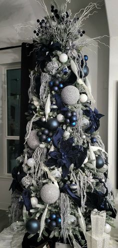 a black and white christmas tree decorated with blue, silver and white ornaments on it