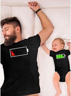 a man laying on top of a bed next to a baby in a black shirt