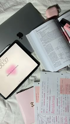 an apple laptop computer sitting on top of a bed next to papers and other items