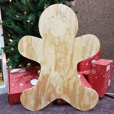 a wooden cutout of a gingerbread man next to presents under a christmas tree