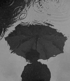 a black umbrella is reflected in the water