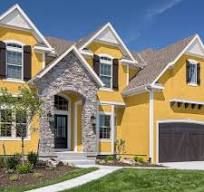 a yellow house with black shutters and two car garage doors on the front door