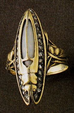 An Art Nouveau Beetle ring, by René Lalique, circa 1903. Gold, opal and diamonds. Signed LALIQUE. Gold ring with slim pointed beetle motif, the curved gold body set with an opal and edged with diamonds, the stylised antennae soaring backwards to form the outline of the insect. Source: The Jewellery of René Lalique, by Vivienne Becker. #Lalique #ArtNouveau #ring Beetle Ring, Lalique Jewelry, Rene Lalique, Gold Bodies, Insect Jewelry