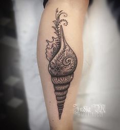 a black and white tattoo on the leg of a woman with an ornate cone design