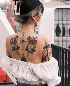 the back of a woman's shoulder with tattoos on her upper and lower half