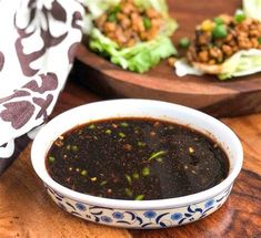 a white bowl filled with soup next to lettuce and other food on a wooden table