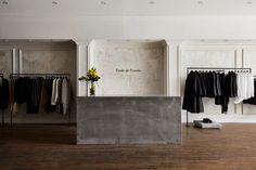 an empty clothing store with clothes on racks and flowers in vases next to the counter