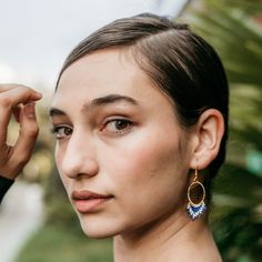 a young woman is posing for the camera with her hand on her head and wearing earrings