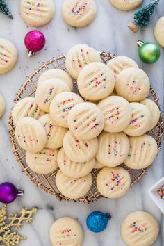 cookies with sprinkles in a basket on a marble table next to christmas decorations