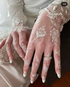 a woman wearing white lace gloves with flowers on her fingers and hands, while sitting down