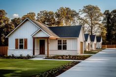 a row of white houses sitting next to each other on a lush green field with trees in the background