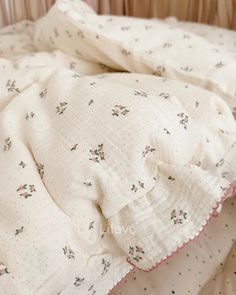 an unmade crib with white sheets and pink trimmings on the edges